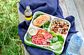 Lunch box with stewed chicken quinoa with vegetables and salad. Outdoors shot