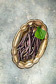 Purple bean pods in tray top view