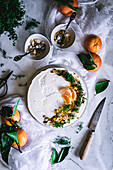Tasty appetizing decorated with mandarin green and nuts tangerine cake and whole citruses knife bowl with spoon on table