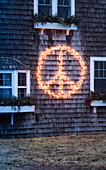 Peace symbol made from fairy lights on shingle facade of house