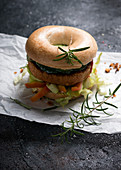 A vegan tofu and bean patty served in a bagel with salad