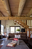 Rustikaler Couchtisch und Couch in offenem Wohnraum mit Holzbalkendecke