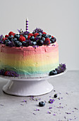 A rainbow cake topped with fresh berries
