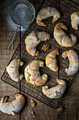 Walnut pastries with icing sugar on a cooling rack