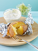 A baked potato with a cream cheese and herb dip