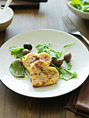 Heart-shaped semolina fritters on herb salad with olives