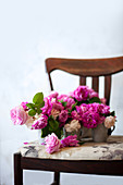Pink roses in metal vases on chair