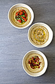 Three Bowls of hummus with various toppings