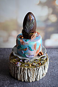 A mini Easter cake topped with a peacock feather chocolate egg