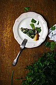 From above portion of tasty vegetarian dish with fresh parsley placed on plate on shabby tabletop