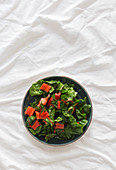 From above bowl with healthy salad from fresh ripe chard placed on wrinkled white fabric