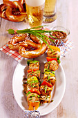 Bavarian white sausage and vegetables skewers with a white beer marinade, mustard, vegetables, pretzel and chives