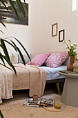 Pink pillows on sofa bed and grey side table in feminine apartment