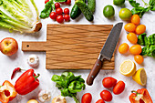 Fresh vegetables, salad leaves and greens, cutting board with chefs knife