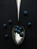 Blueberries and spoon on black background