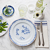 A place setting with floral plates, cutlery and a cloth napkin