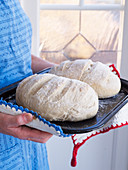 Woman holding bread on baking tray