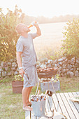 Man drinking beer while having barbecue
