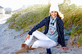 Junge Frau in Stoffhose, Sweatshirt und Kapuzenjacke mit Pudelmütze