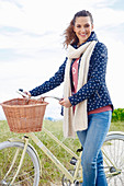 Junge Frau in Jeans, Sweatshirt und Kapuzenjacke an Fahrrad