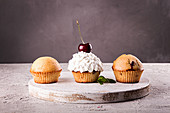 Muffins and cupkake with whipped cream decorated with cherry