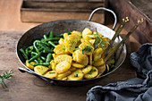 Fried potatoes with green beans in an iron pan