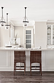 L-shaped kitchen counter with bar stools below pendant lamps