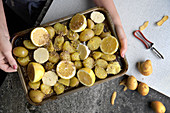 Frau hält Backblech mit Zitronenkartoffeln