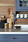 Storage jars and chopping boards in country-house kitchen with blue cupboards