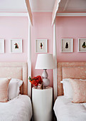 Round side table between two post beds in pink bedroom