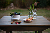 Frische Pflaumen in einem Topf und Pflauemnkuchen in einer Metallschale auf Gartentisch