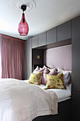 Double bed surrounded by dark grey fitted cupboards