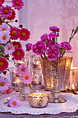 Nelken, Margeriten und Teelichter als romantische Tischdekoration