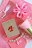 Romantic arrangement in pink with string of lettered beads and bag of sweets