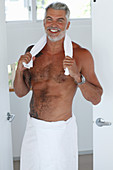 Grauhaariger Mann mit nacktem Oberkörper und Badetuch um die Hüften