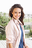 A young brunette woman wearing a blue t-shirt with a pale pink shirt blouse