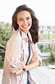 A young brunette woman wearing a blue t-shirt with a pale pink shirt blouse