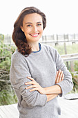 A young brunette woman wearing a grey woollen jumper with an under shirt