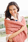 A young brunette woman wearing a light shirt blouse with a salmon pink woollen shawl