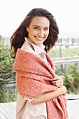A young brunette woman wearing a light shirt blouse with a salmon pink woollen shawl