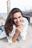 A young brunette woman wearing wearing a white tunic with a woollen jumper over her shoulders