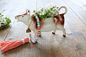 Fruit blossom in cow-shaped milk jug on wooden table
