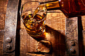 Bourbon pouring into rocks glass on a bourbon barrel