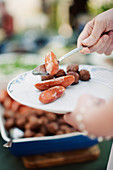 Hand putting sausages on plate