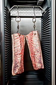 Beef halves in a stainless steel cupboard
