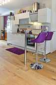 Purple bar stools at counter in kitchen area of open-plan interior