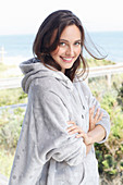 A young brunette woman wearing a light grey hoodie