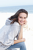 A young brunette woman wearing a light grey hoodie and jeans