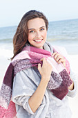 A young brunette woman wearing a light grey hoodie and a scarf