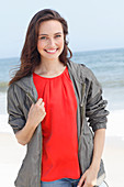 A young brunette woman wearing a red blouse, a grey windbreaker